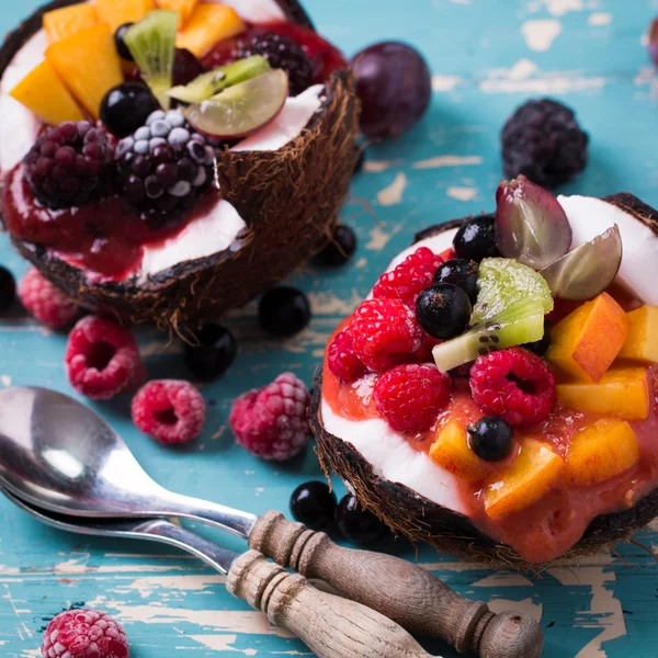 Blueberries and strawberries served in two coconuts on a wooden background. — Stock Photo, Image