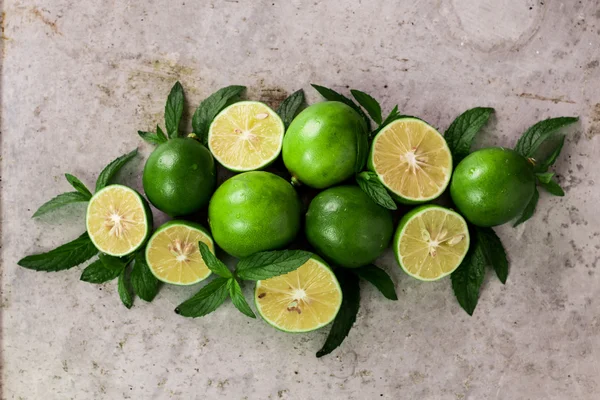 Lime background. Fresh limes with slices and mint leaves around.