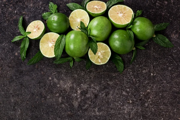 Lime background. Fresh limes with slices and mint leaves around.