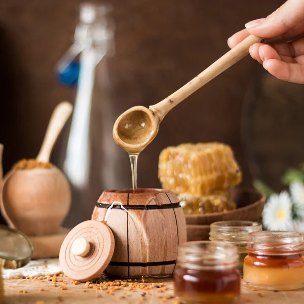 Honey background. Natural honey comb, glass jarand wooden bowls. On wooden rustic table. Soft focus — Stock Photo, Image