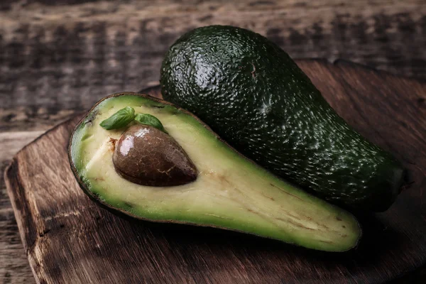 Lebensmittelhintergrund mit frischer Bio-Avocado auf altem Holztisch, Draufsicht, Kopierraum — Stockfoto