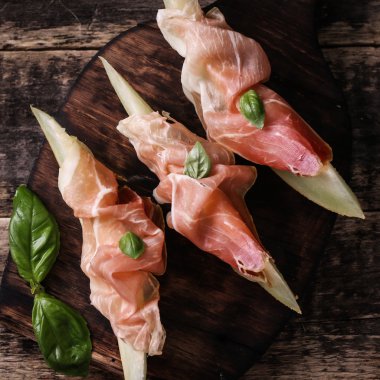 Prosciutto ve vintage ahşap zemin üzerine fesleğen taze kavun