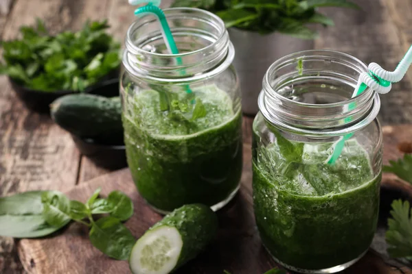 Frischer grüner Smoothie mit Strohhalmen auf einem Holztisch, gesunde vegane Kost — Stockfoto