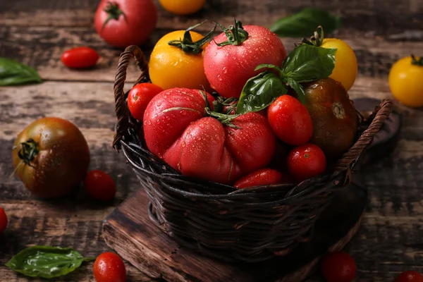 Barevné rajčata, červená rajčata, žlutá rajčata, oranžová rajčata, zelená rajčata. Rajčata pozadí. Vintage dřevěné pozadí — Stock fotografie