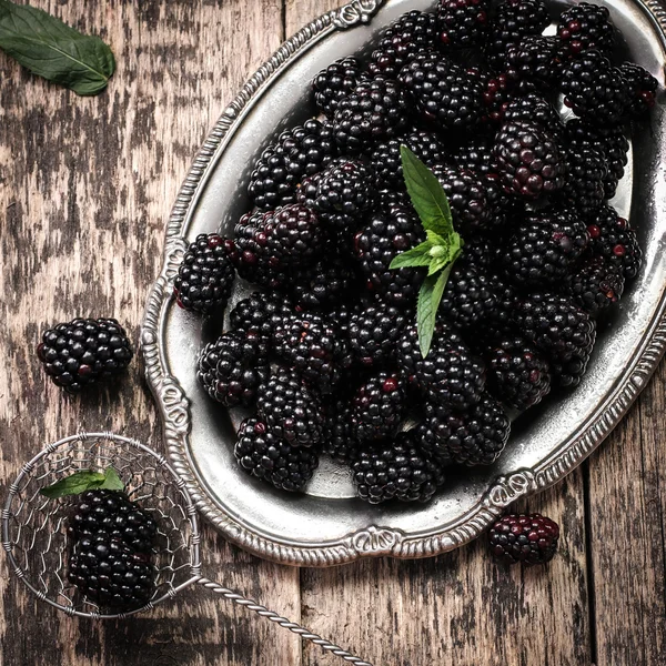 Ripe blackberries in a ceramic bowl on burlap cloth over wooden background close up. Rustic style, Selective focus — Stock Photo, Image