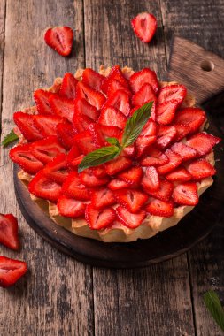 Çilek ve ahşap zemin üzerine krem şanti ile tart