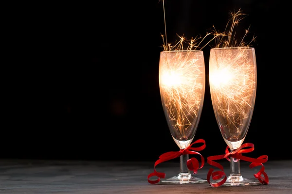 Бокалы шампанского и бенгальские огни на черном фоне, веселая рождественская концепция — стоковое фото