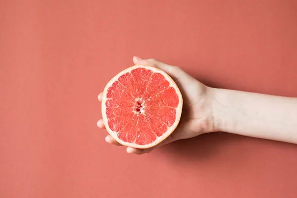 Mãos de uma jovem segurando uma toranja vermelha. conceito de alimentação saudável — Fotografia de Stock