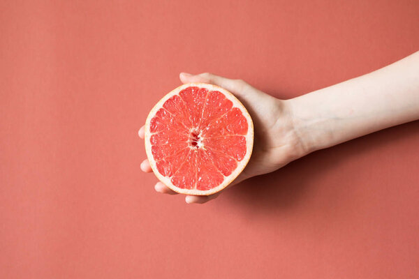 Hands of a young woman holding a red grapefruit. healthy food concept