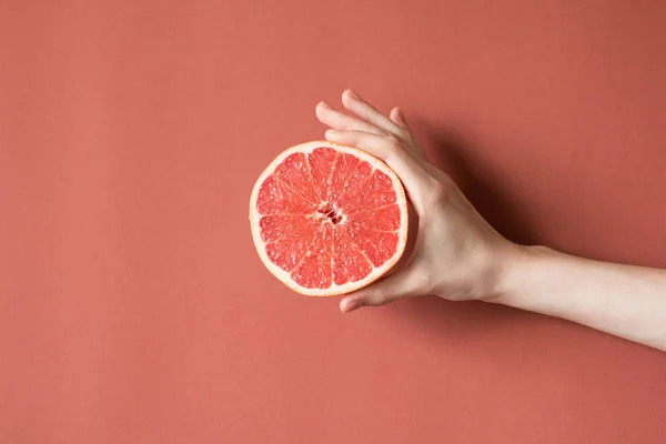 Mãos de uma jovem segurando uma toranja vermelha. conceito de alimentação saudável — Fotografia de Stock