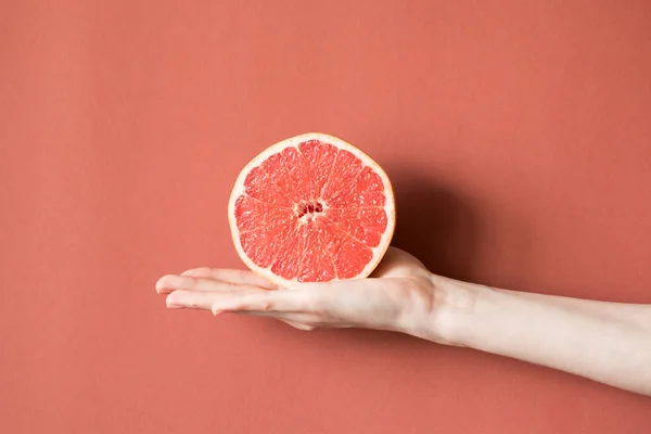 Mâinile unei tinere care ţine un grapefruit roşu. Conceptul alimentar sănătos — Fotografie, imagine de stoc