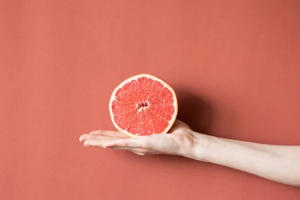 Mãos de uma jovem segurando uma toranja vermelha. conceito de alimentação saudável — Fotografia de Stock