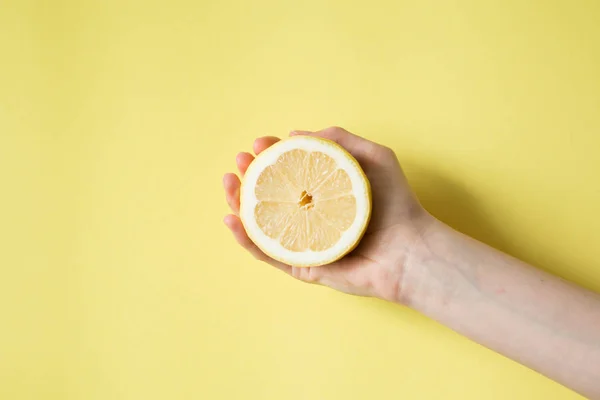 Lemon di tangan wanita pada latar belakang kuning — Stok Foto