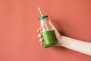 Smoothie shake renkli duvara tutan kadın el. İçme yeşil sağlıklı güler yüzlü kavramı.