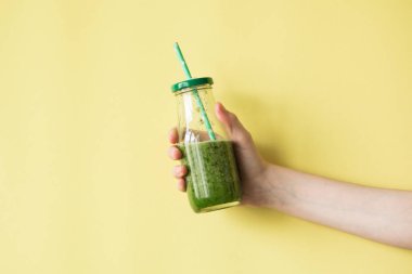 Smoothie shake renkli duvara tutan kadın el. İçme yeşil sağlıklı güler yüzlü kavramı.