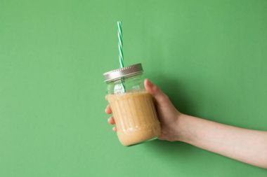 Smoothie shake renkli duvara tutan kadın el. İçme sarı sağlıklı güler yüzlü kavramı.