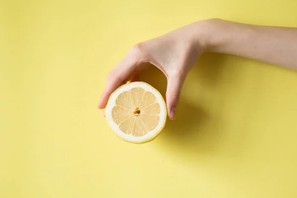 Lemon di tangan wanita pada latar belakang kuning — Stok Foto