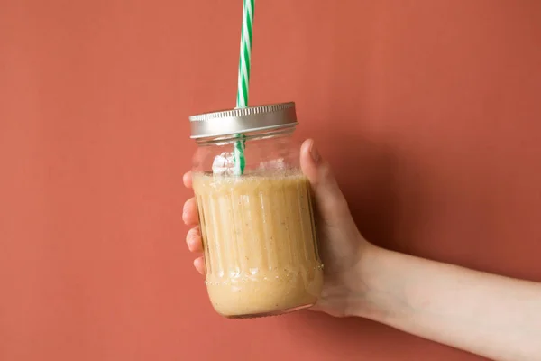 Smoothie shake renkli duvara tutan kadın el. İçme sarı sağlıklı güler yüzlü kavramı.