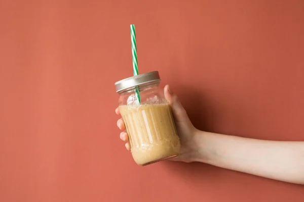 Smoothie shake renkli duvara tutan kadın el. İçme sarı sağlıklı güler yüzlü kavramı.