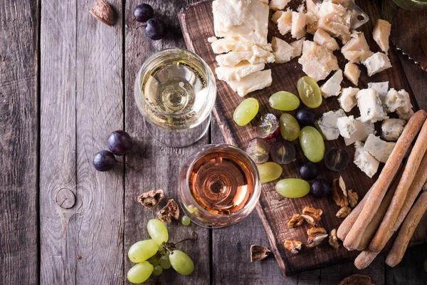 Verschiedene Arten von Käse, Wein, Obst und Snacks auf einem rustikalen Holztisch. Stilllebenkonzept — Stockfoto