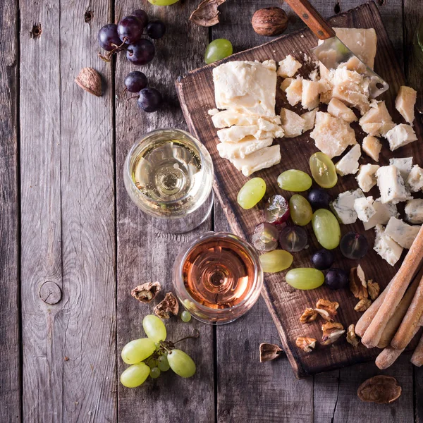Διαφορετικά είδη τυριών, κρασί, φρούτα και σνακ σε ρουστίκ ξύλινα πίνακα. έννοια ακόμα ζωή — Φωτογραφία Αρχείου