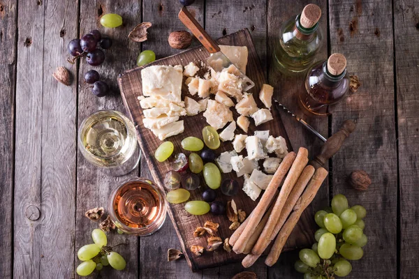 Verschiedene Arten von Käse, Wein, Obst und Snacks auf einem rustikalen Holztisch. Stilllebenkonzept — Stockfoto