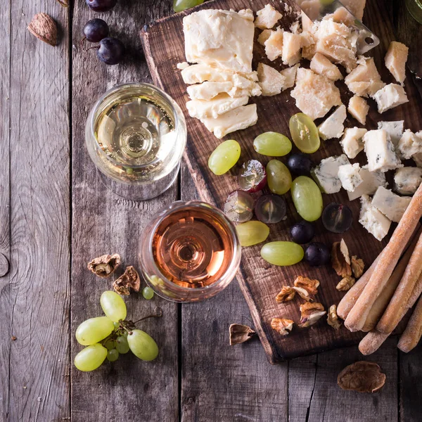 Verschiedene Arten von Käse, Wein, Obst und Snacks auf einem rustikalen Holztisch. Stilllebenkonzept — Stockfoto