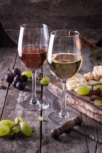 Verschiedene Arten von Käse, Wein, Obst und Snacks auf einem rustikalen Holztisch. Stilllebenkonzept — Stockfoto