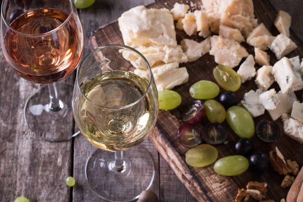 Verschiedene Arten von Käse, Wein, Obst und Snacks auf einem rustikalen Holztisch. Stilllebenkonzept — Stockfoto