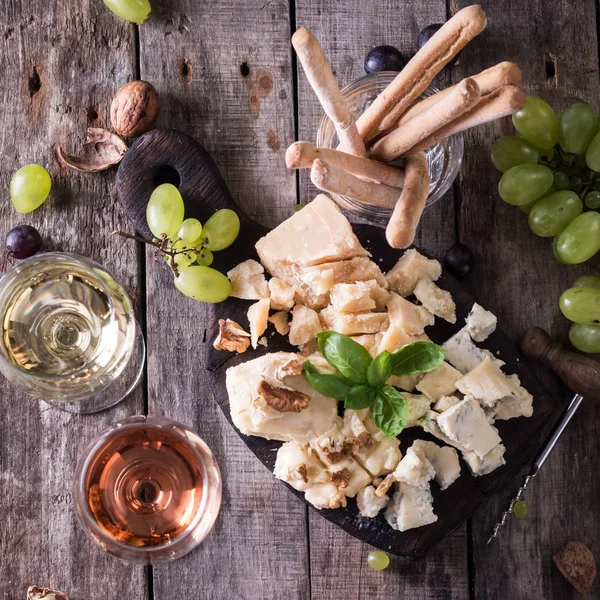 Verschiedene Arten von Käse, Wein, Obst und Snacks auf einem rustikalen Holztisch. Stilllebenkonzept — Stockfoto