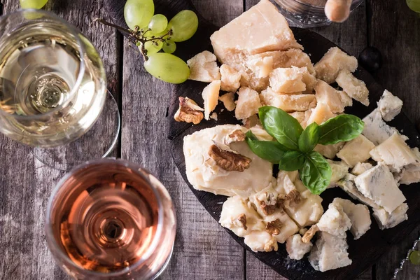 Verschiedene Arten von Käse, Wein, Obst und Snacks auf einem rustikalen Holztisch. Stilllebenkonzept — Stockfoto