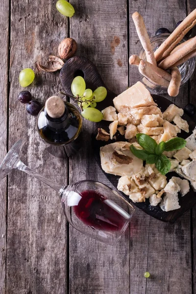 Διαφορετικά είδη τυριών, κρασί, φρούτα και σνακ σε ρουστίκ ξύλινα πίνακα. έννοια ακόμα ζωή — Φωτογραφία Αρχείου