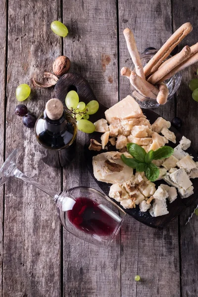 Verschiedene Arten von Käse, Wein, Obst und Snacks auf einem rustikalen Holztisch. Stilllebenkonzept — Stockfoto