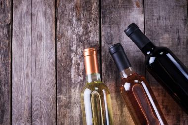 kırmızı, pembe ve beyaz şişe şarap ahşap masa arka plan üzerinde. Natürmort kavramı