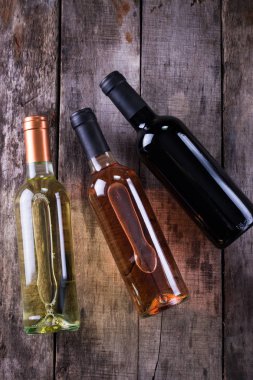 kırmızı, pembe ve beyaz şişe şarap ahşap masa arka plan üzerinde. Natürmort kavramı