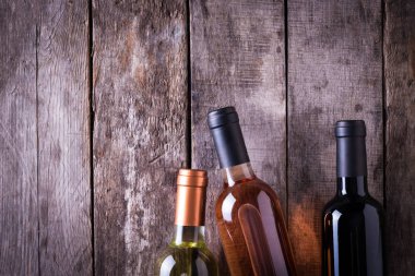 kırmızı, pembe ve beyaz şişe şarap ahşap masa arka plan üzerinde. Natürmort kavramı