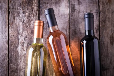 kırmızı, pembe ve beyaz şişe şarap ahşap masa arka plan üzerinde. Natürmort kavramı