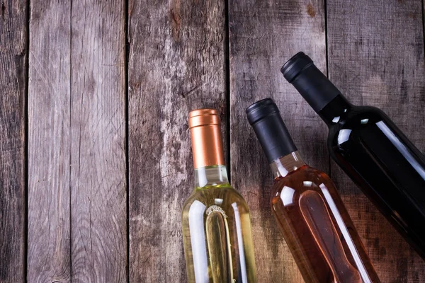 kırmızı, pembe ve beyaz şişe şarap ahşap masa arka plan üzerinde. Natürmort kavramı