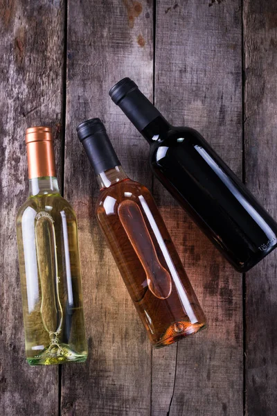 kırmızı, pembe ve beyaz şişe şarap ahşap masa arka plan üzerinde. Natürmort kavramı