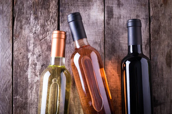 kırmızı, pembe ve beyaz şişe şarap ahşap masa arka plan üzerinde. Natürmort kavramı