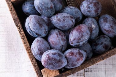 Erikler. Bahçedeki mavi ve mor erikler ahşap masada..