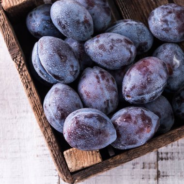 Erikler. Bahçedeki mavi ve mor erikler ahşap masada..