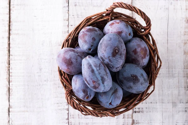 Des prunes. Prunes bleues et violettes dans le jardin sur table en bois. — Photo