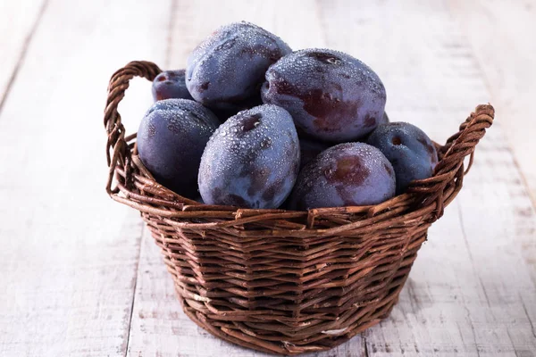 Des prunes. Prunes bleues et violettes dans le jardin sur table en bois. — Photo