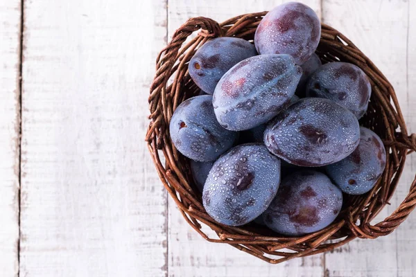 Des prunes. Prunes bleues et violettes dans le jardin sur table en bois. — Photo