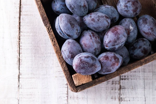 Des prunes. Prunes bleues et violettes dans le jardin sur table en bois. — Photo