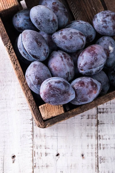 Des prunes. Prunes bleues et violettes dans le jardin sur table en bois. — Photo