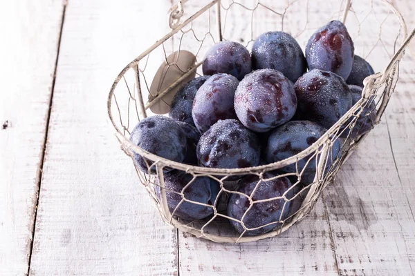 Des prunes. Prunes bleues et violettes dans le jardin sur table en bois. — Photo