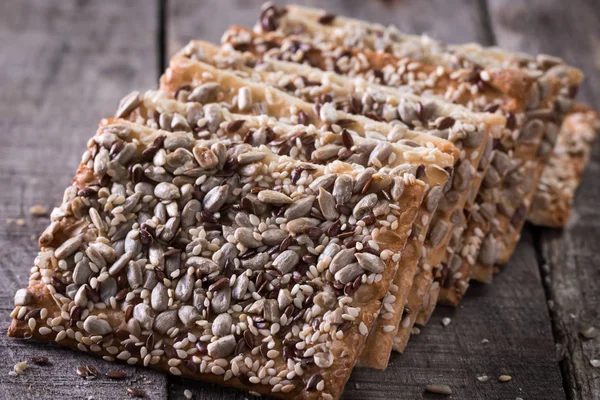 Gevrek crispbread ahşap arka plan üzerinde. Sağlıklı snack: gevrek gevrek tahıllı Mısır gevreği keten tohumu, susam, ayçiçeği tohumu protein ekmek bar. Stok Fotoğraf