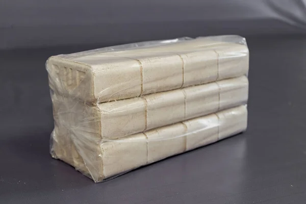 Alternatif yakıt, ekolojik yakıt, biyolojik yakıt. Odun talaşı sobaları için briketler. Isı çıkışı iyi olan bir yanık izi. Yeşil bir arka planda talaş briketleri.